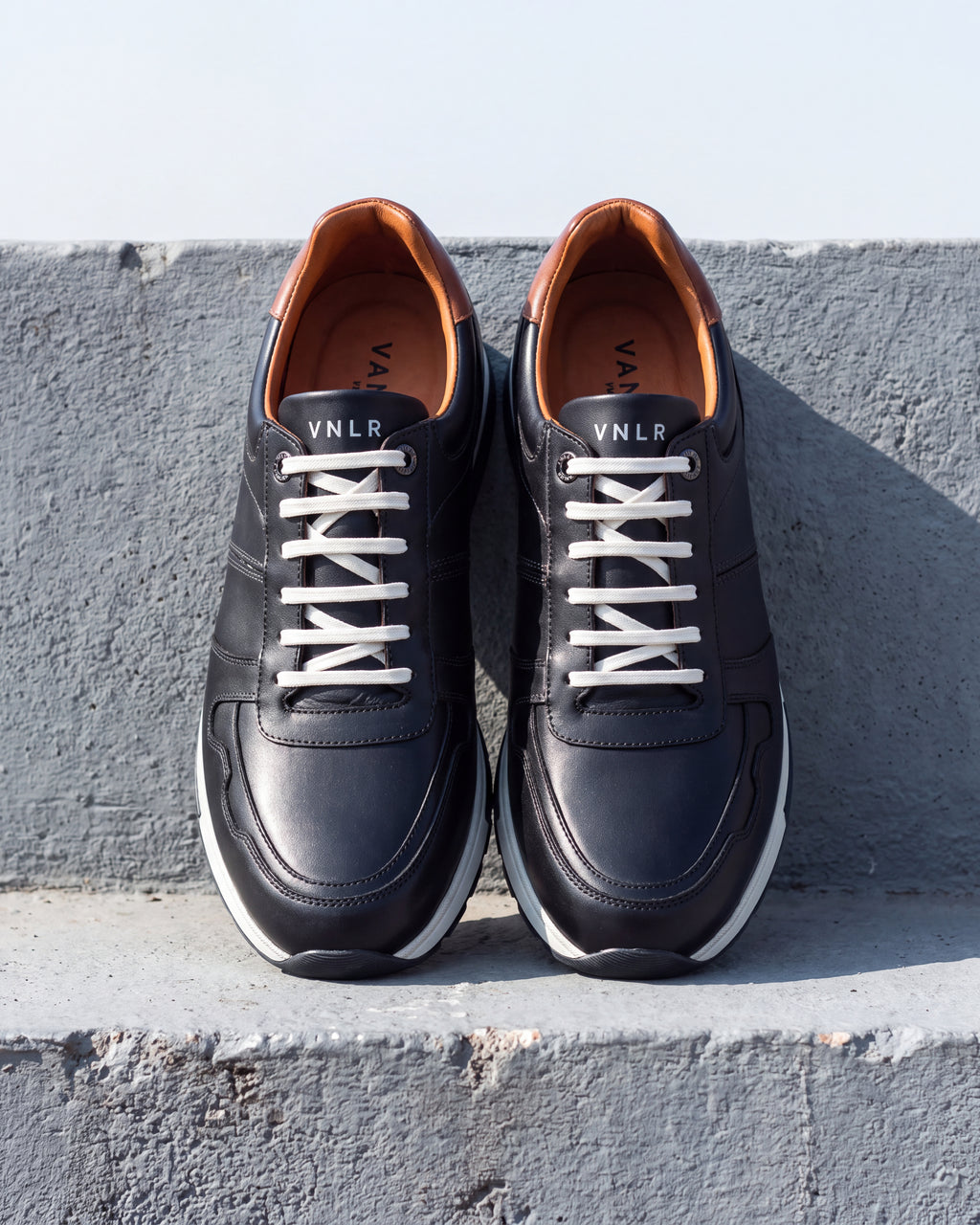 Donker Blauw gladleren Positano sneaker – close-up van het paar op ruw beton