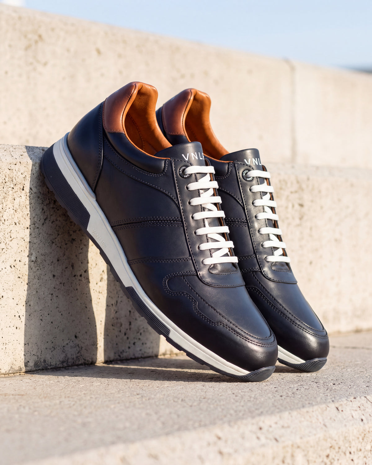 Donker Blauw gladleren Positano sneaker – detail van het paar op ruw beton