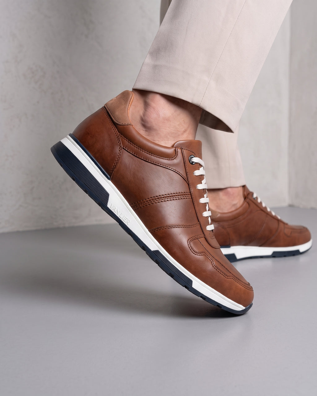 Cognac gladleren Positano sneaker – close-up van het paar in een betonnen atelier