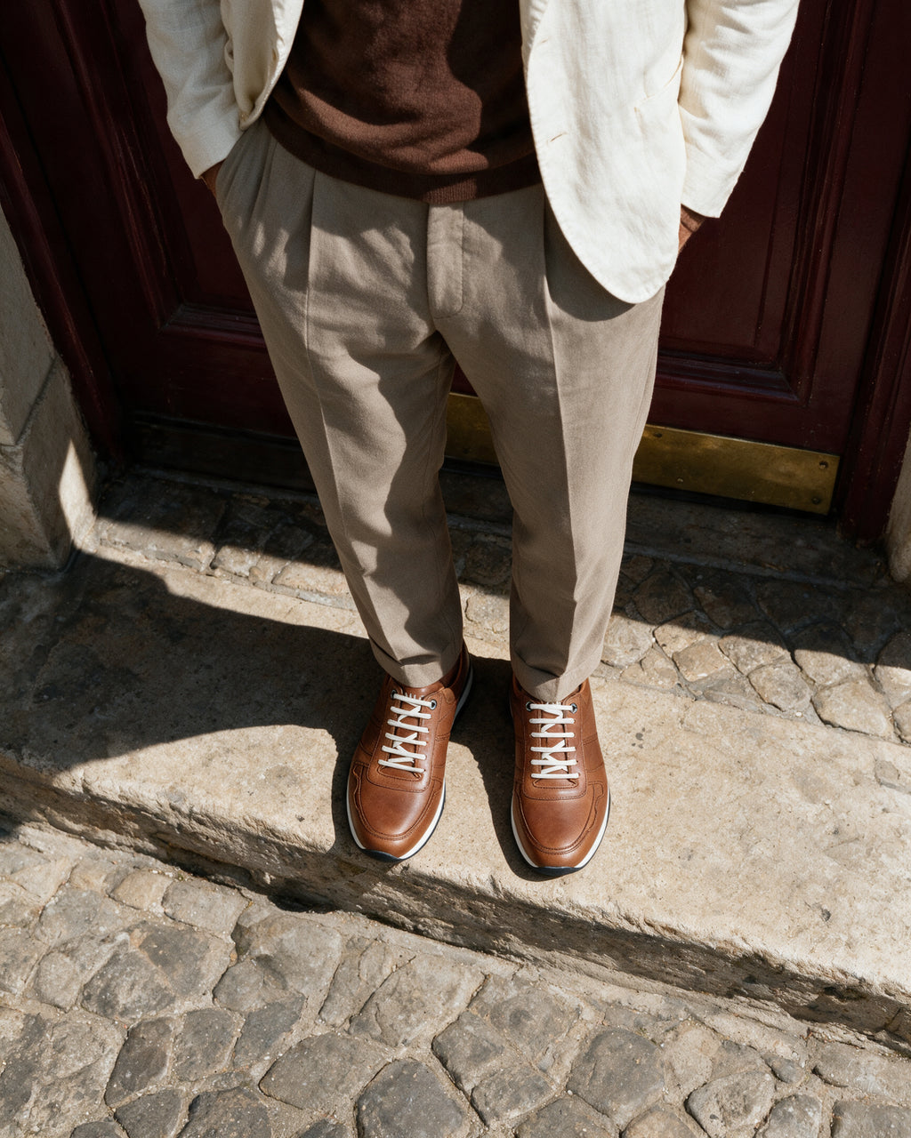 Cognac gladleren Positano sneaker – gedragen, neerkijkend op de drempel, tweede opname