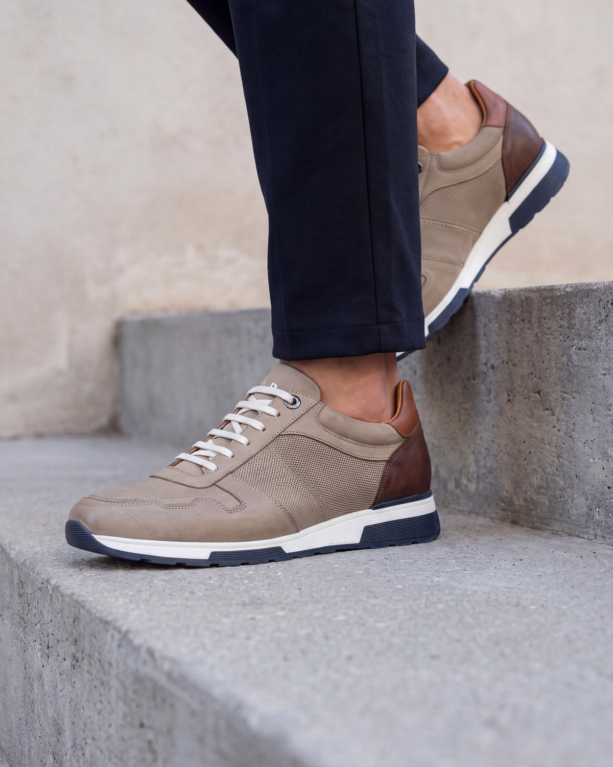Taupe nubuck Positano sneaker – close-up van het paar in een betonnen atelier, andere hoek
