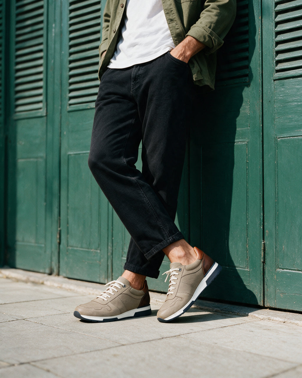 Taupe nubuck Positano sneaker – gedragen, leunend tegen een winkelpui