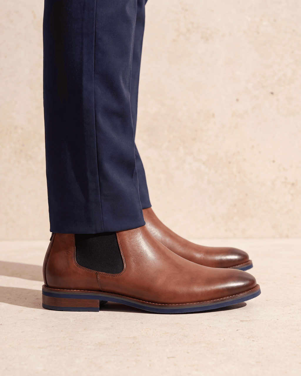 Cognac gladleren Amalfi chelsea boot – close-up van het paar op een kalkstenen vloer