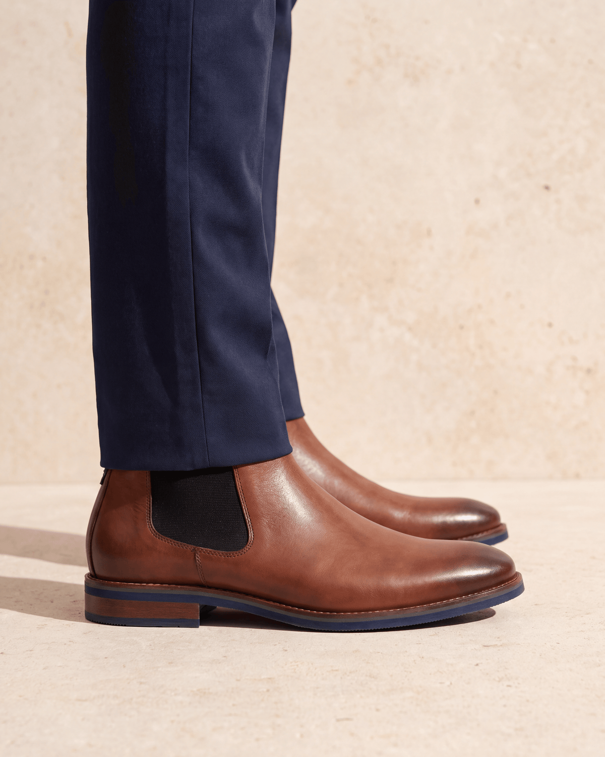 Cognac gladleren Amalfi chelsea boot – close-up van het paar op een kalkstenen vloer