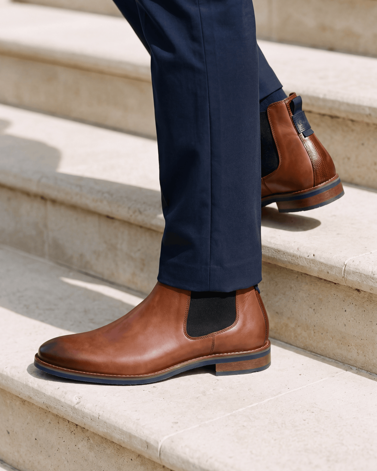 Cognac gladleren Amalfi chelsea boot – close-up van het paar op een kalkstenen vloer, tweede hoek