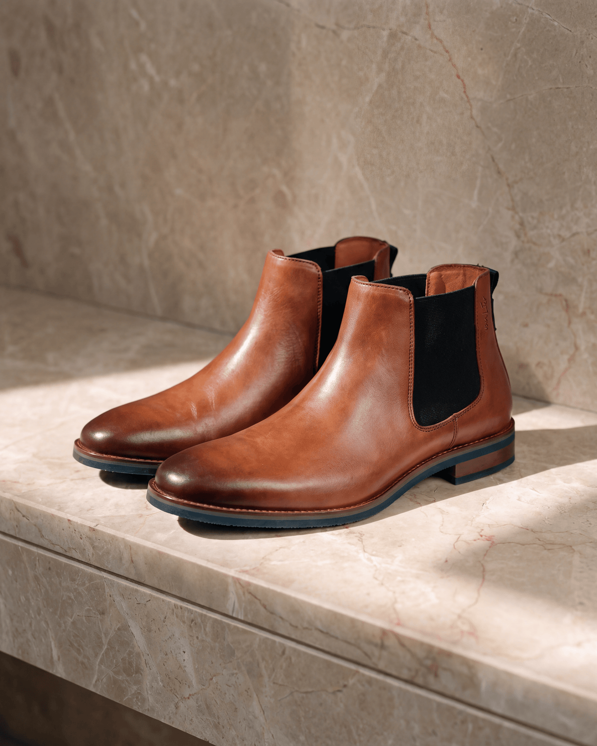 Cognac gladleren Amalfi chelsea boot – stilleven op warm marmer