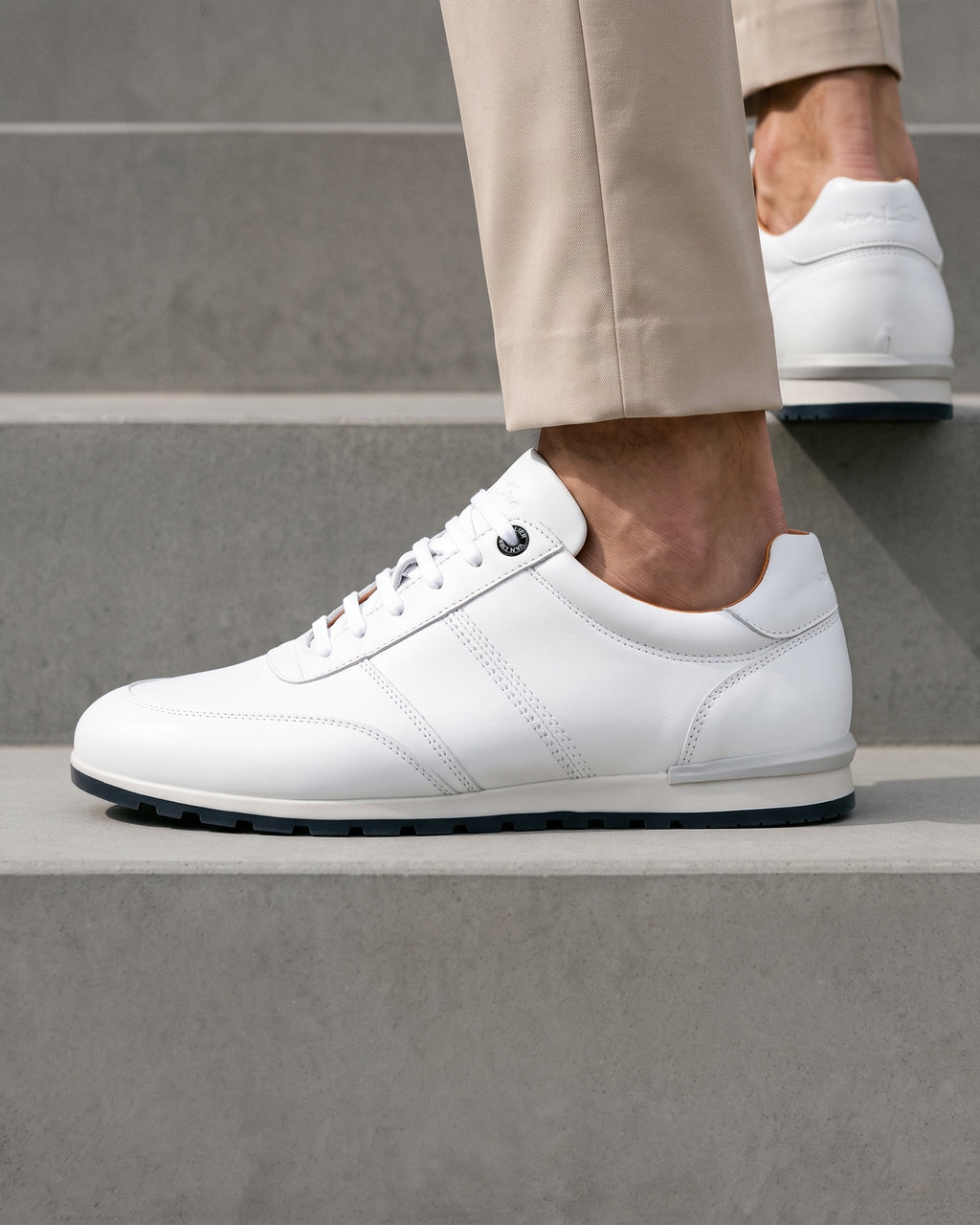 Wit gladleren Anzano sneaker – close-up van het paar op een ruwe betonnen vloer