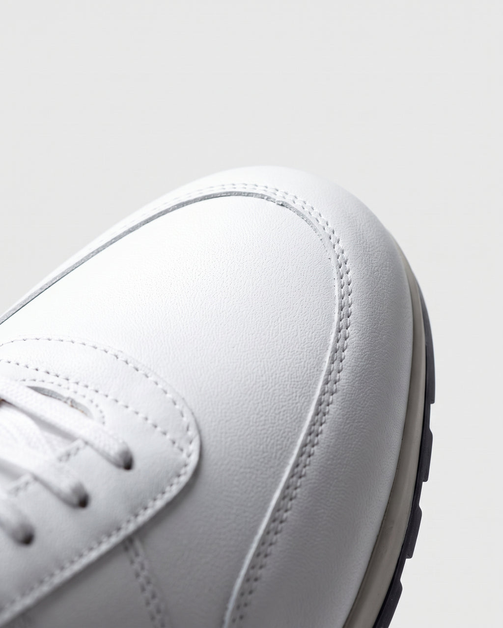 Wit gladleren Anzano sneaker – macro-detail van het paar