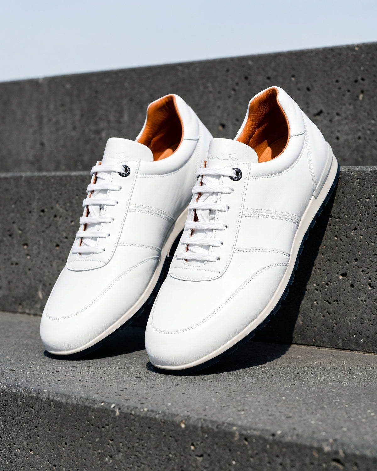 Wit gladleren Anzano sneaker – close-up van het paar op ruw beton