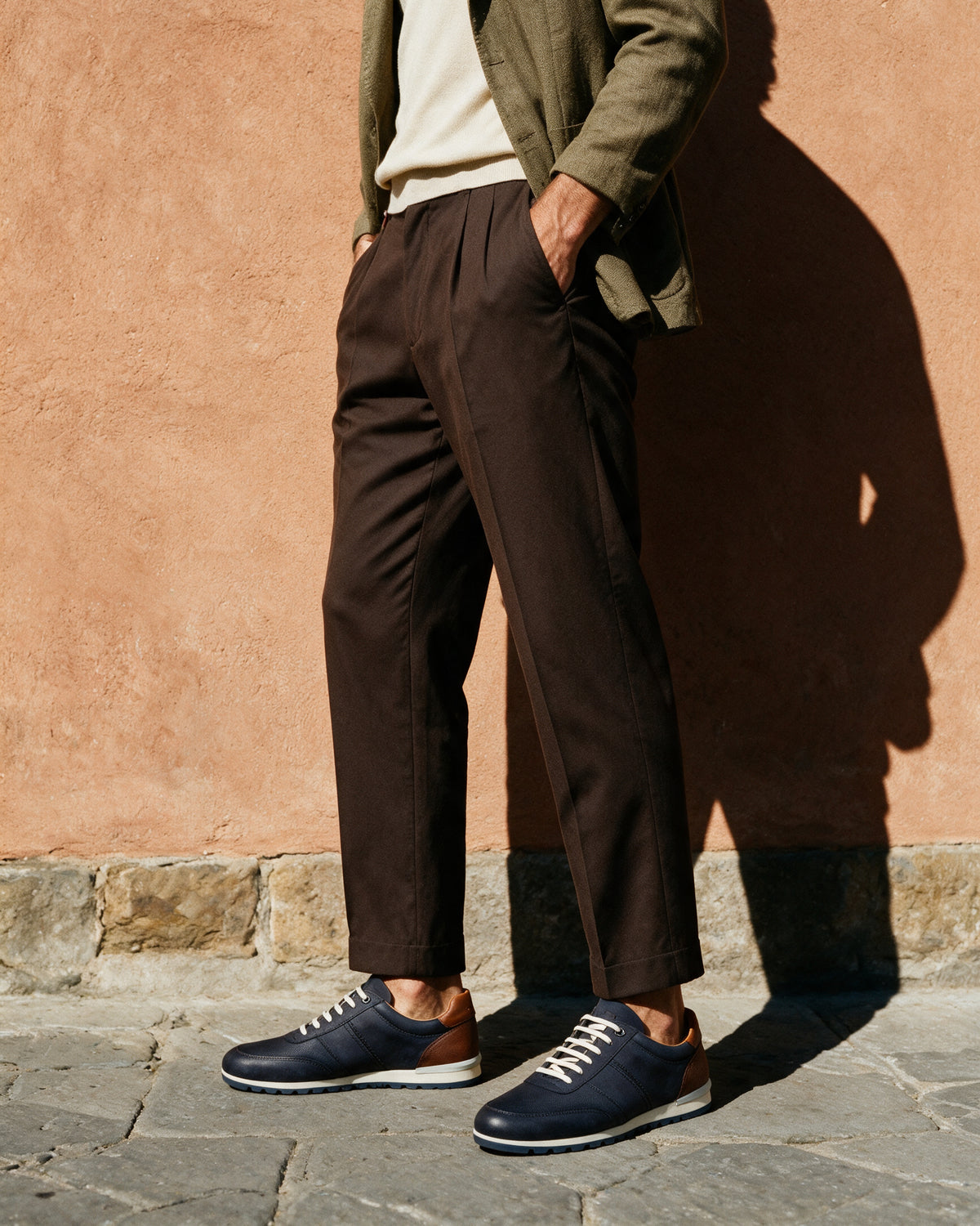 Navy blauw nubuck Anzano sneaker – lifestyle in profiel bij een terracotta muur