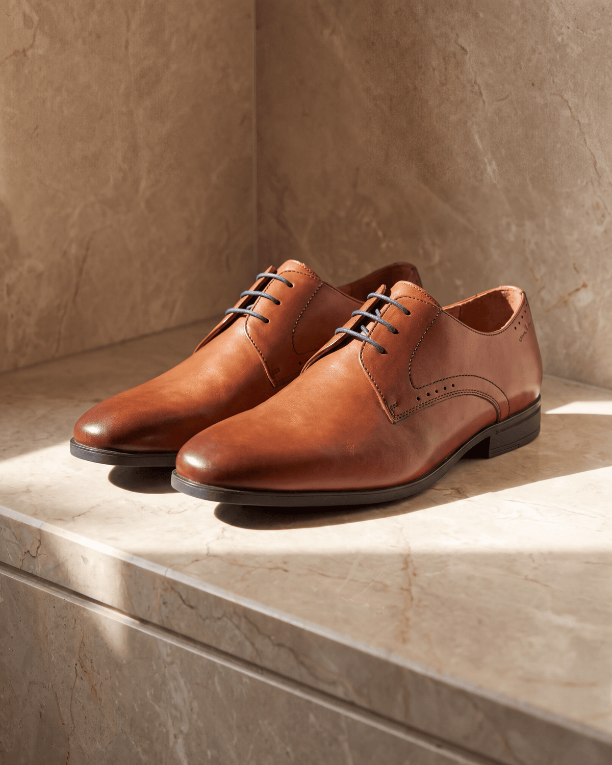Cognac gladleren Portofino veterschoen – het paar op warm marmer