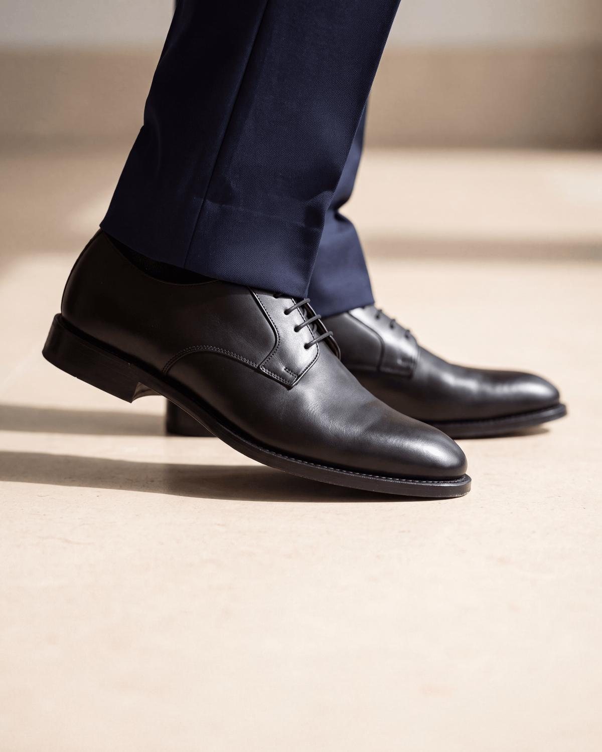 Zwart gladleren Portofino veterschoen – close-up van het paar op kalksteen