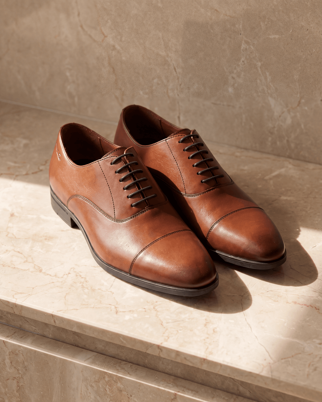 Cognac gladleren Portofino veterschoen – het paar op warm marmer
