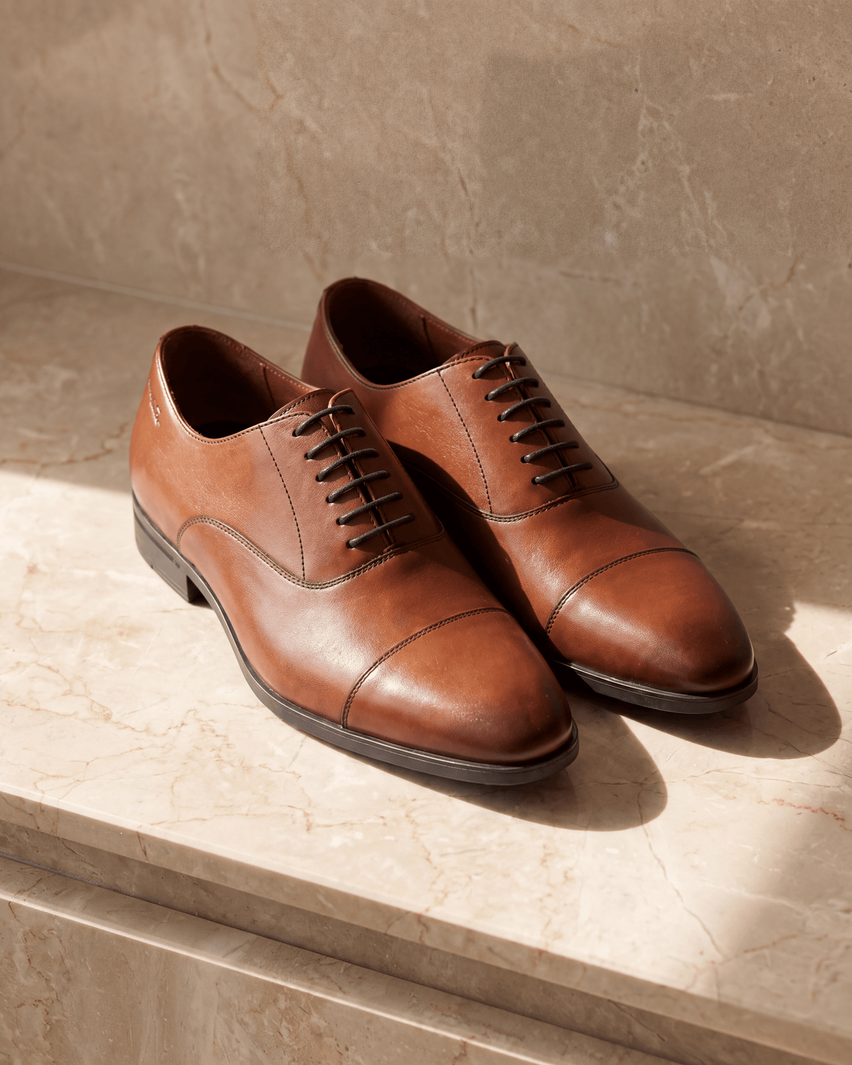 Cognac gladleren Portofino veterschoen – het paar op warm marmer