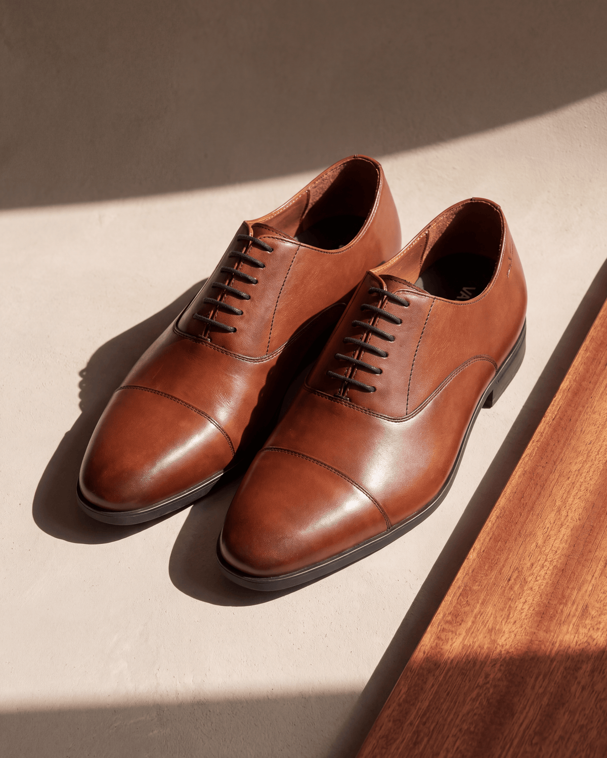 Cognac gladleren Portofino veterschoen – het paar op hout en pleisterwerk