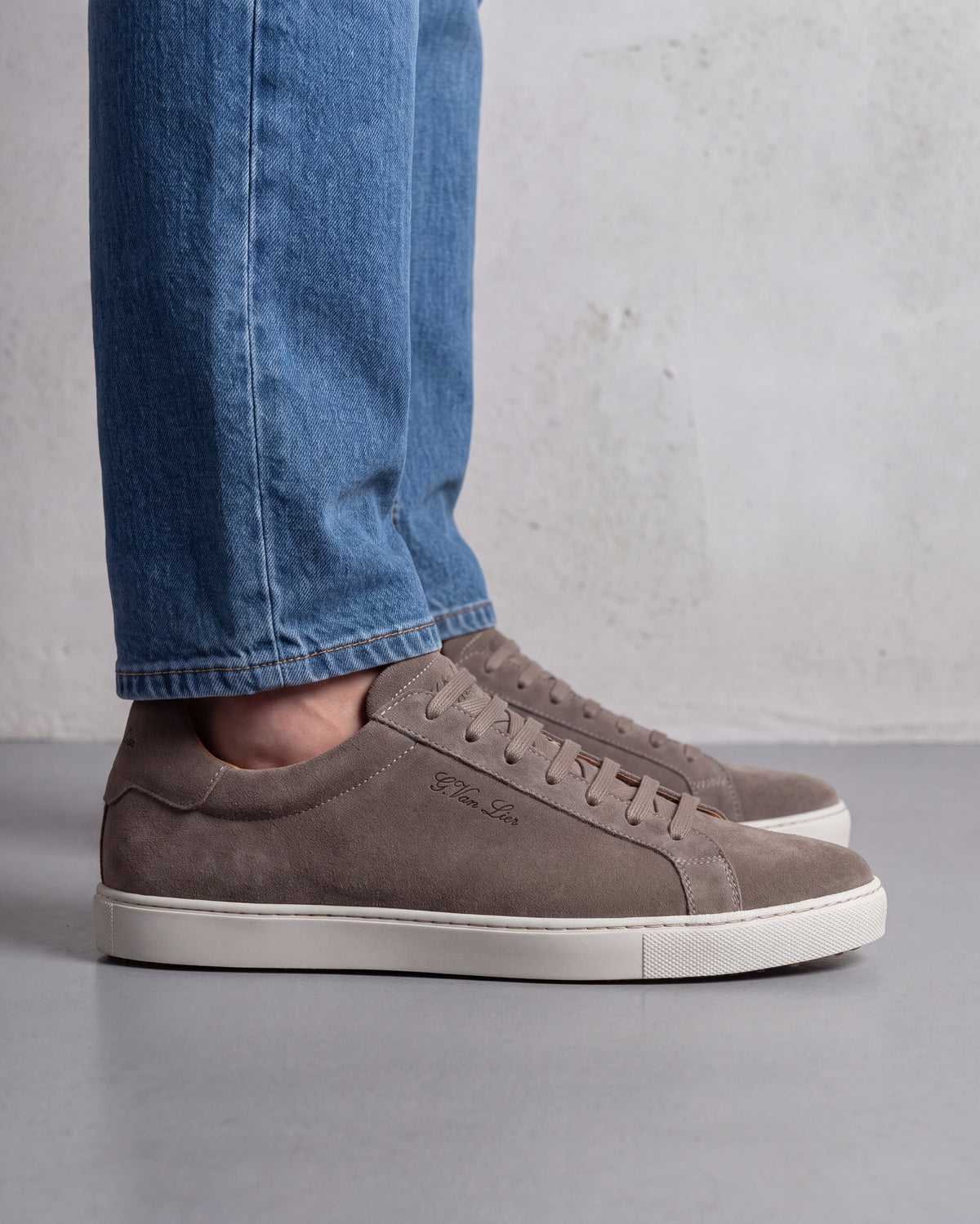 Taupe suède Napoli sneaker – close-up van het paar op beton in een atelier