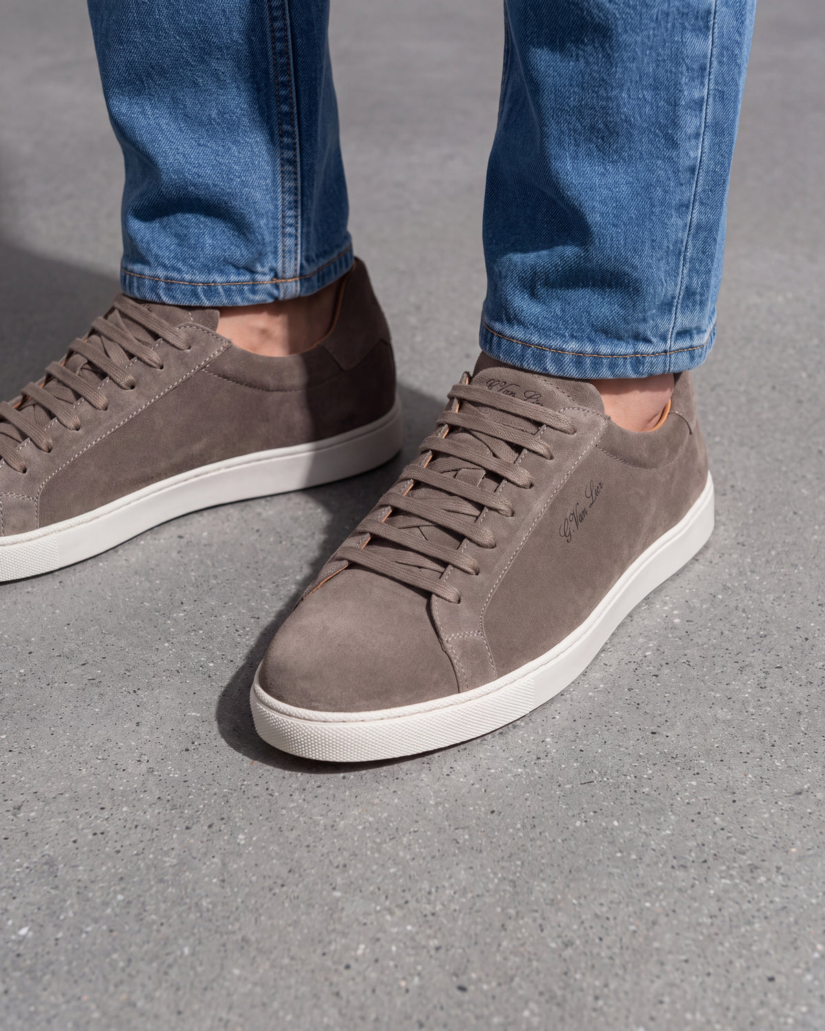 Taupe suède Napoli sneaker – close-up van het paar op een betonnen vloer