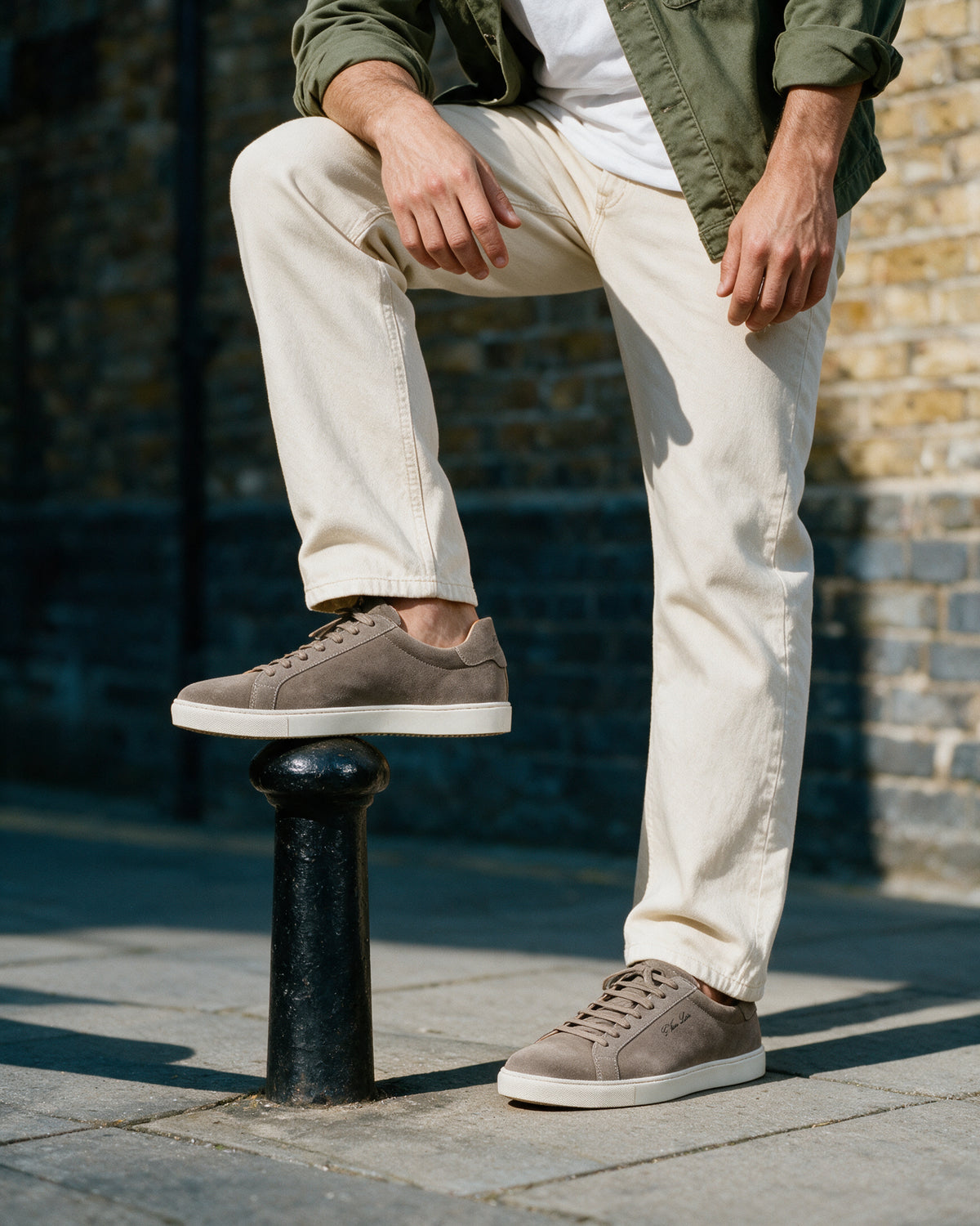 Taupe suède Napoli sneaker – lifestyle met de voet op een paaltje