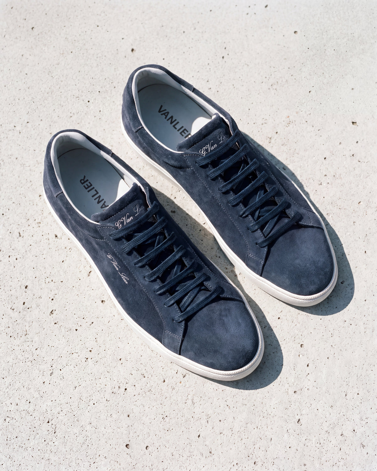 Navy blauw suède Napoli sneaker – close-up van het paar op ruw beton