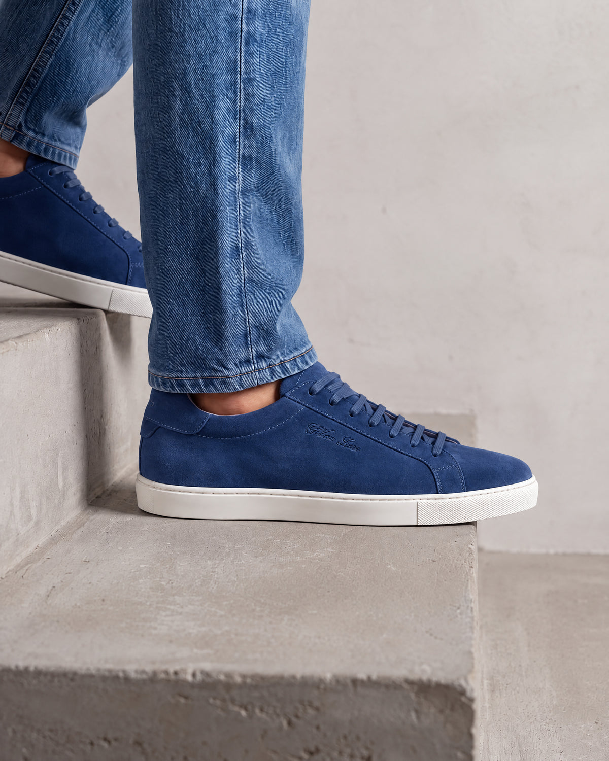 Blauw suède Napoli sneaker – close-up van het paar in een betonnen atelier