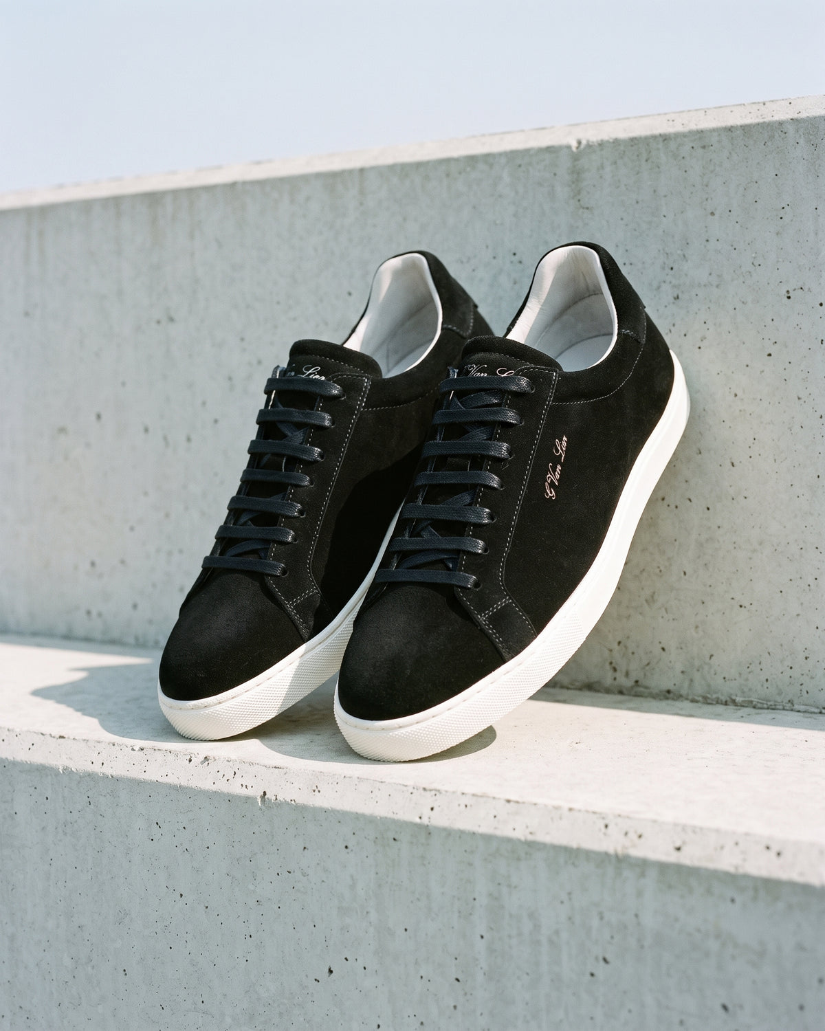 Zwart suède Napoli sneaker – close-up van het paar op ruw beton