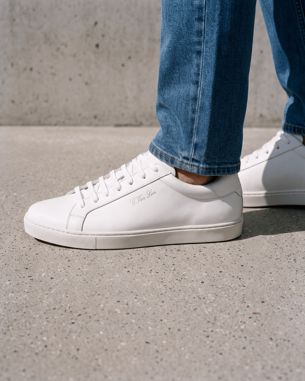 Wit gladleren Napoli sneaker – close-up van het paar op ruw beton