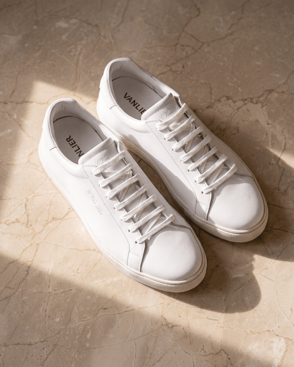 Wit gladleren Napoli sneaker – het paar op warm marmer