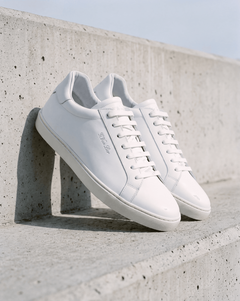 Wit gladleren Napoli sneaker – het paar op ruw beton