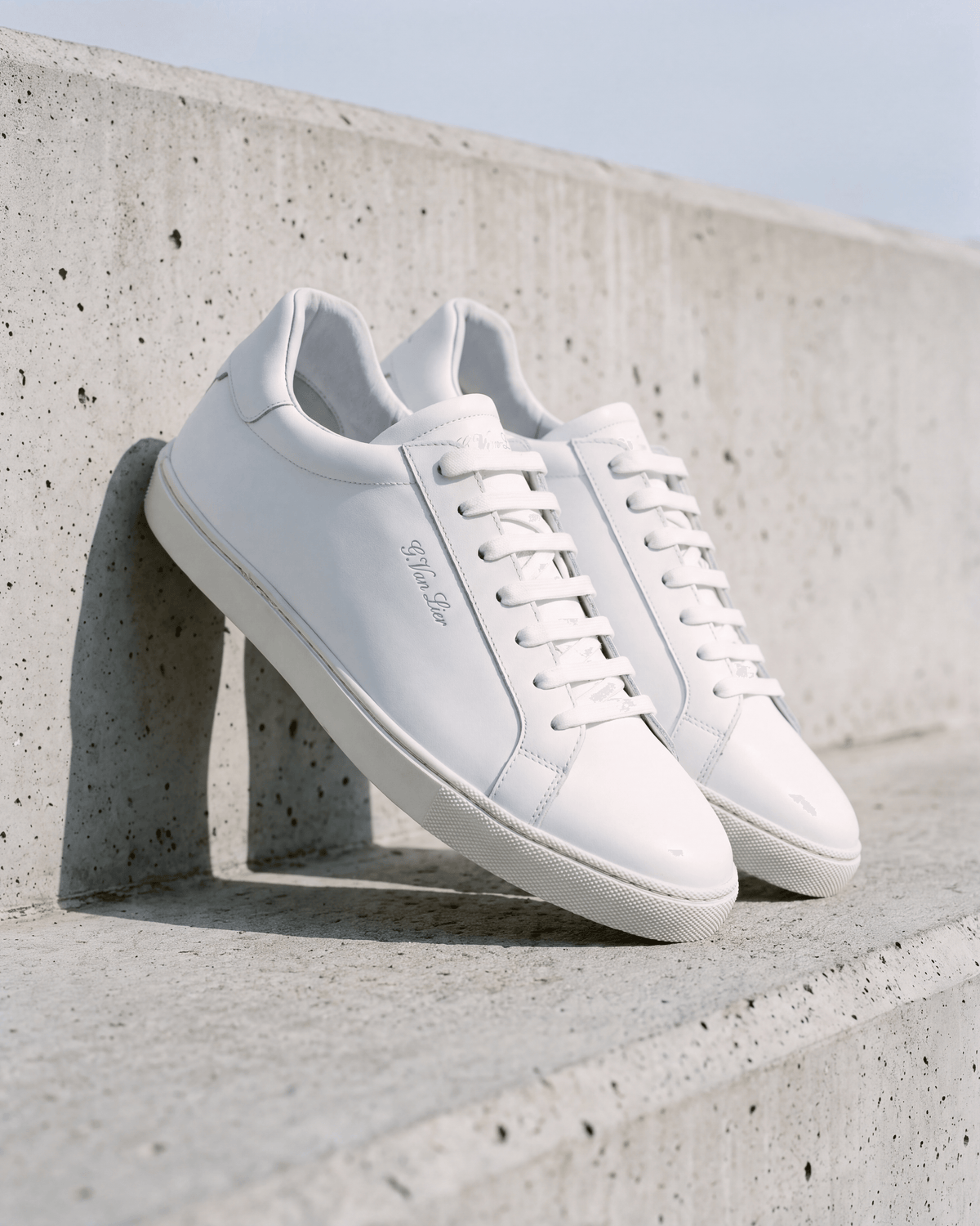 Wit gladleren Napoli sneaker – het paar op ruw beton