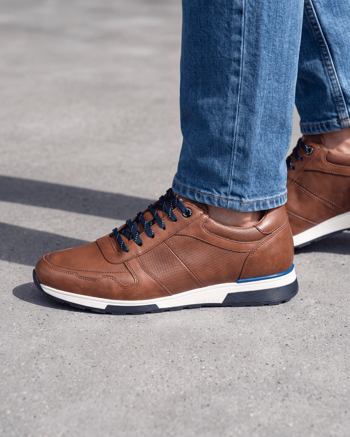 Cognac gladleren Positano sneaker – close-up van het paar op ruw beton