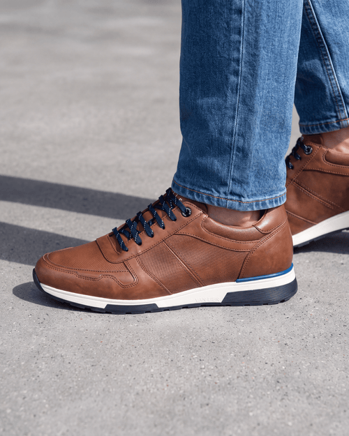 Cognac gladleren Positano sneaker – close-up van het paar op ruw beton