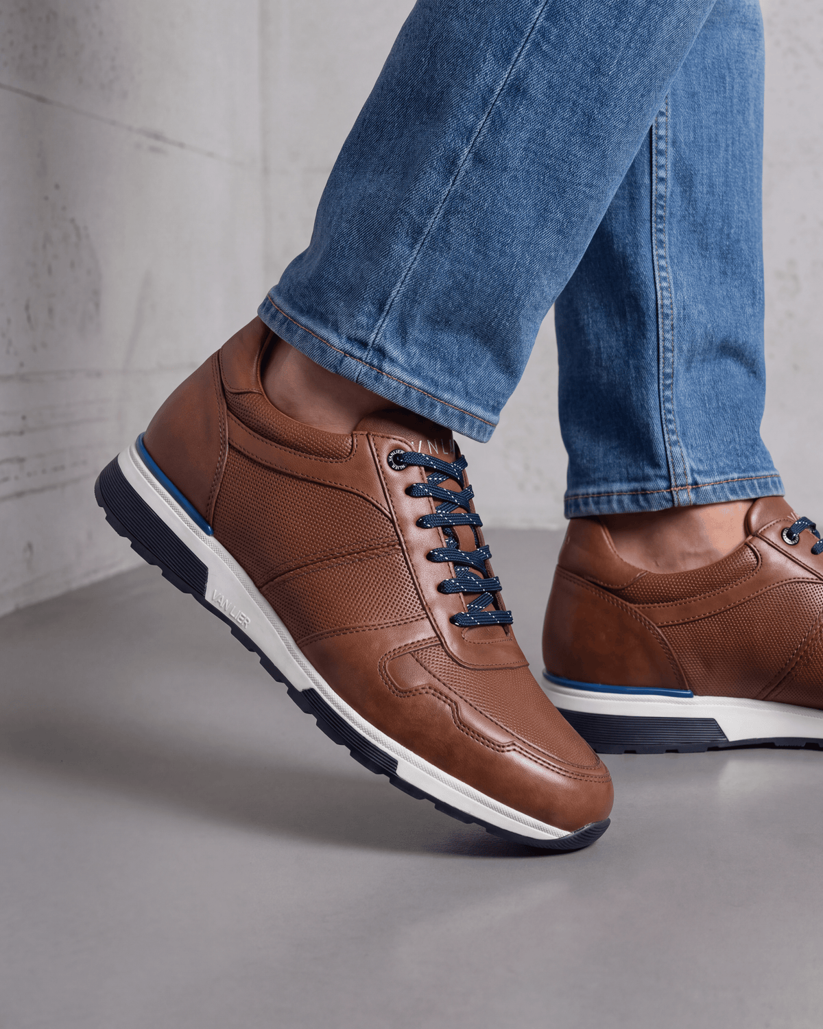 Cognac gladleren Positano sneaker – close-up van het paar op beton in een atelier