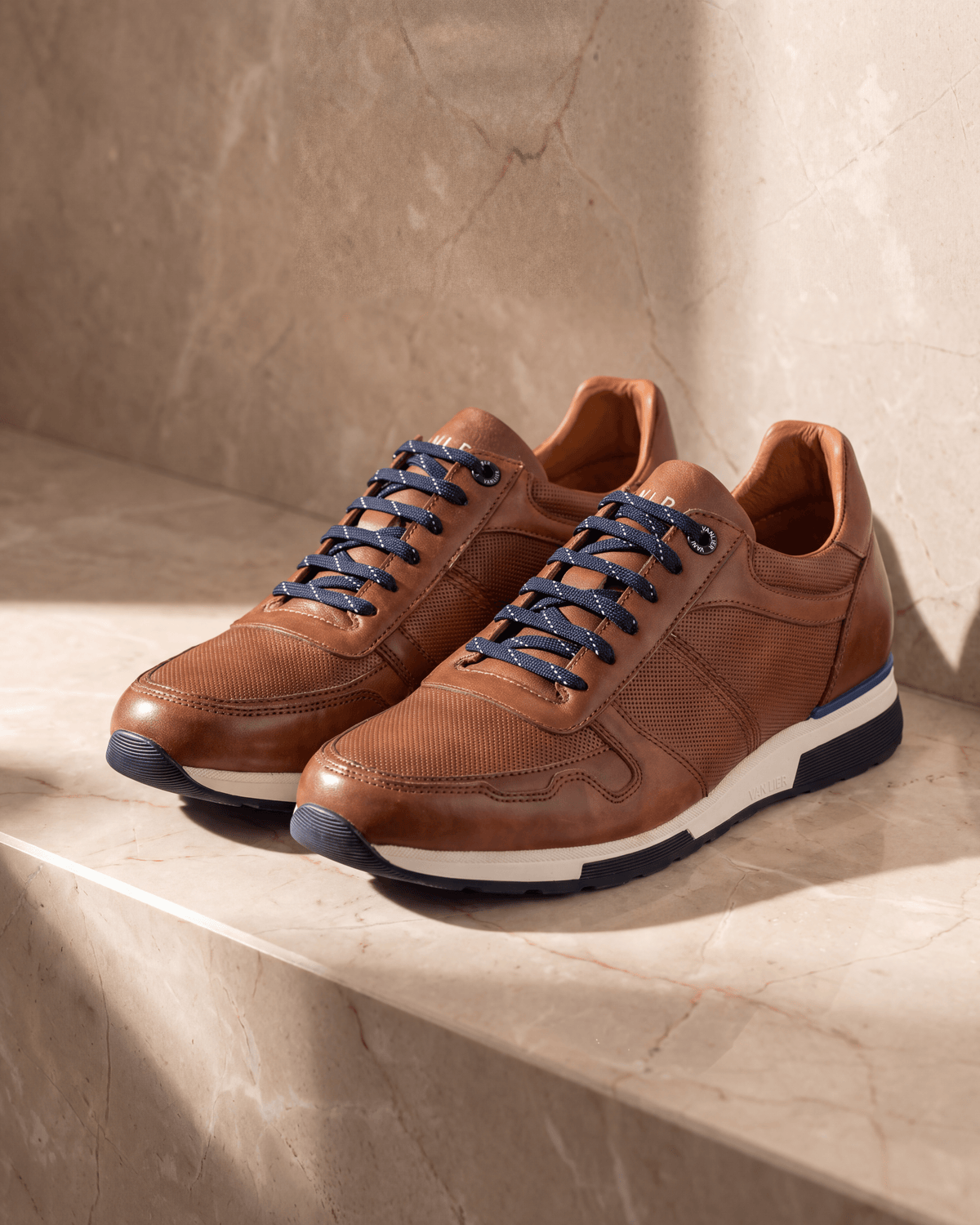 Cognac gladleren Positano sneaker – het paar op warm marmer