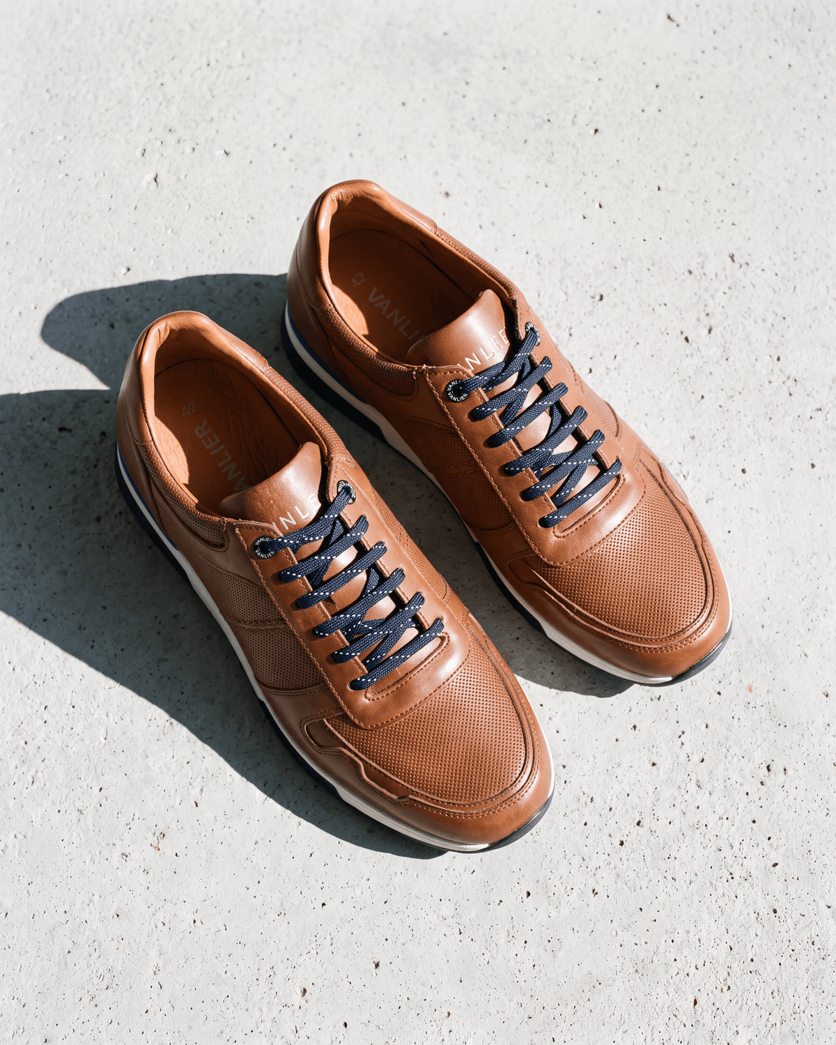 Cognac gladleren Positano sneaker – het paar op ruw beton
