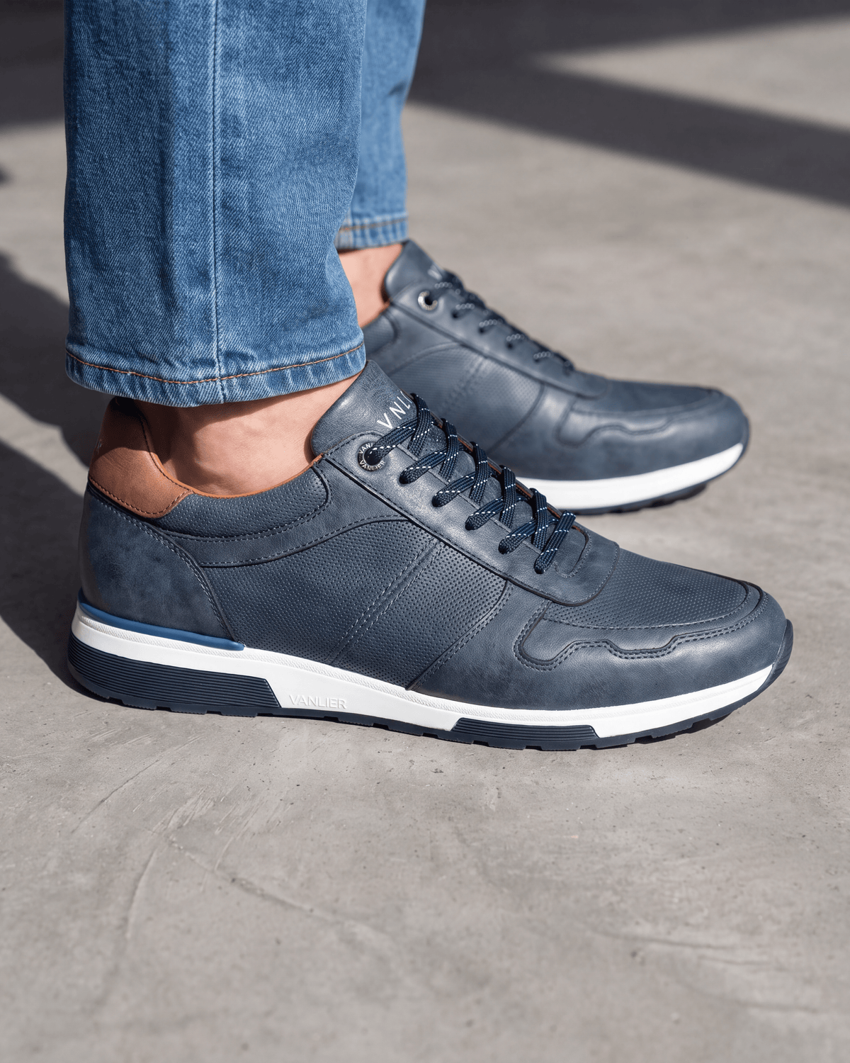Navy blauw gladleren Positano sneaker – close-up van het paar op ruw beton