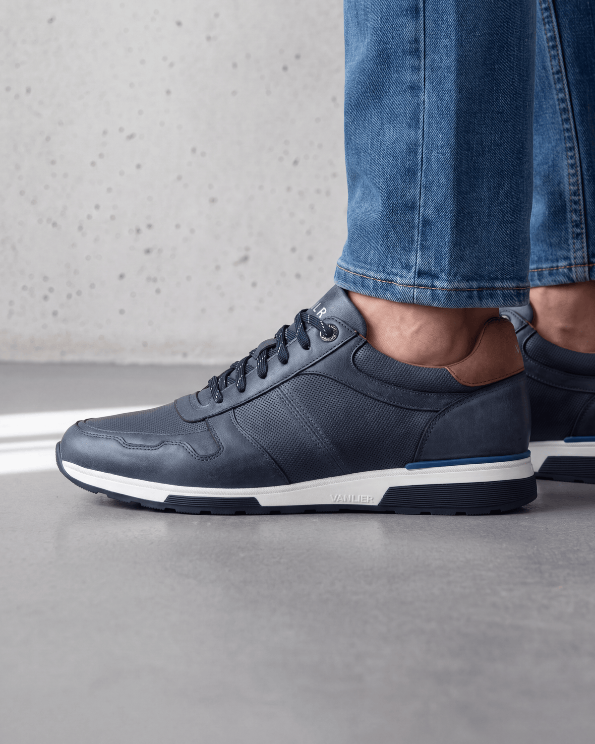 Navy blauw gladleren Positano sneaker – close-up van het paar op beton in een atelier