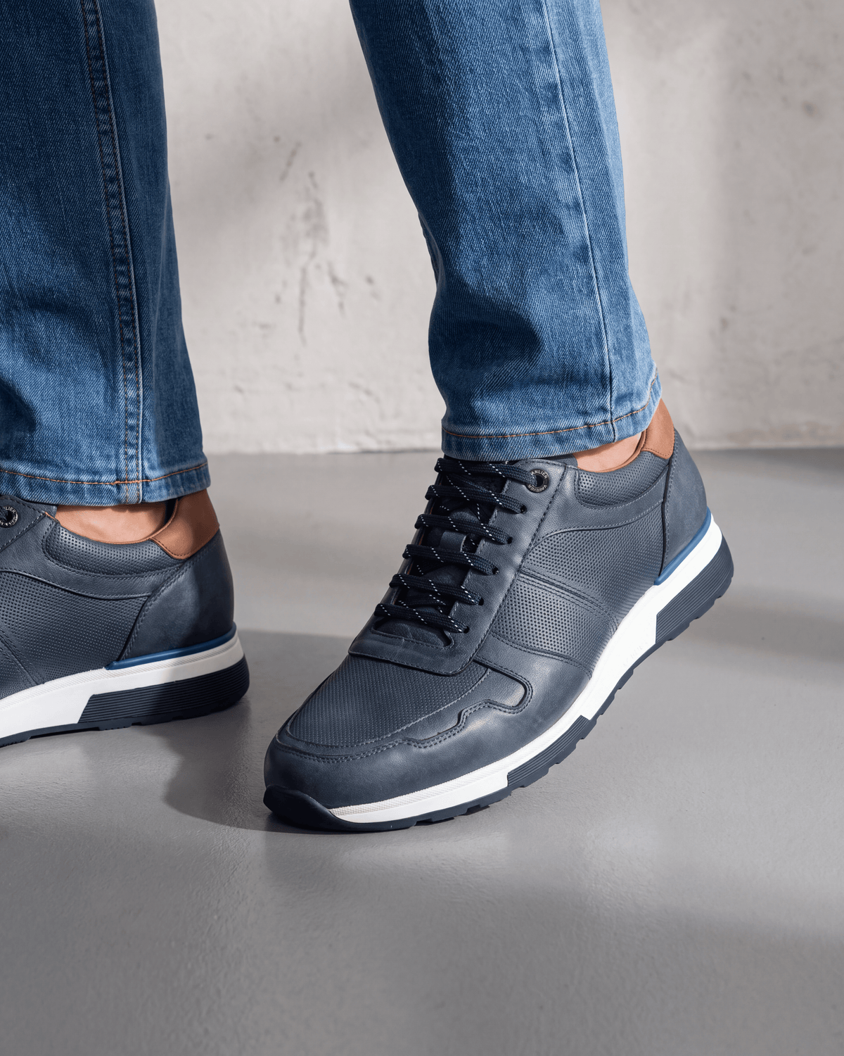 Navy blauw gladleren Positano sneaker – close-up van het paar op beton in een atelier