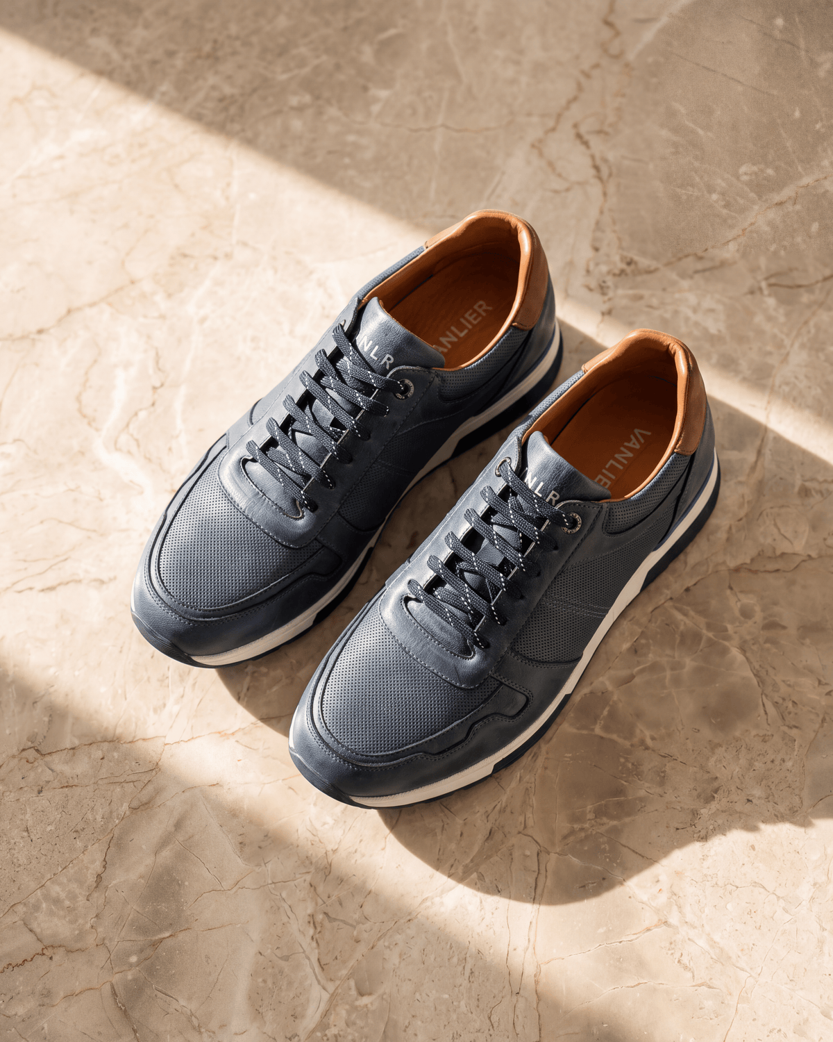 Navy blauw gladleren Positano sneaker – het paar op warm marmer