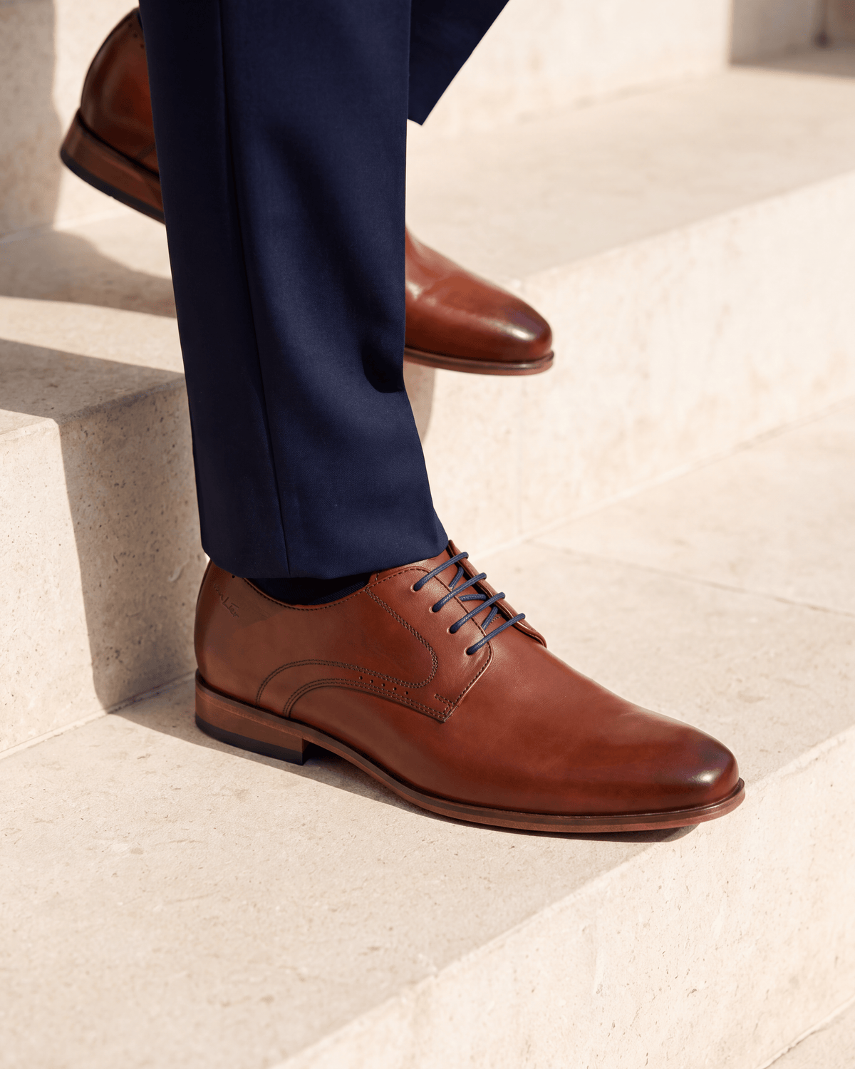 Cognac gladleren Rhodes veterschoen – close-up van het paar op kalksteen