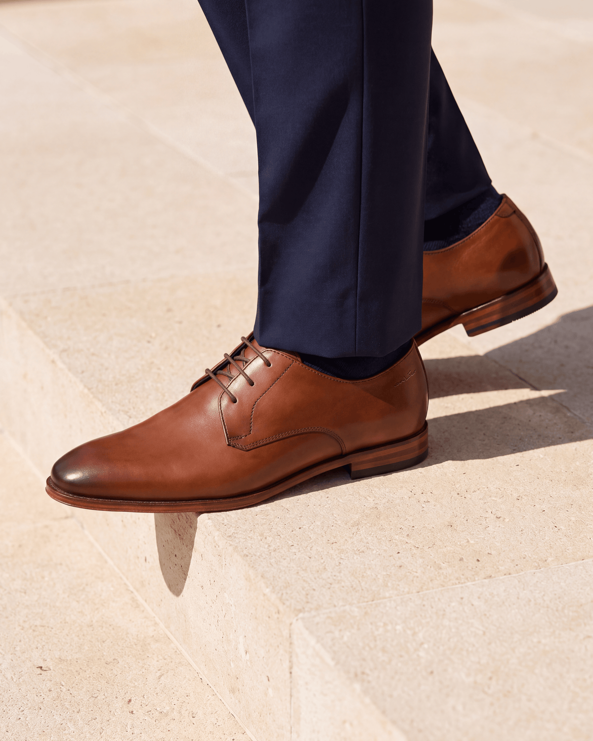 Cognac gladleren Madison veterschoen – close-up van het paar op kalksteen