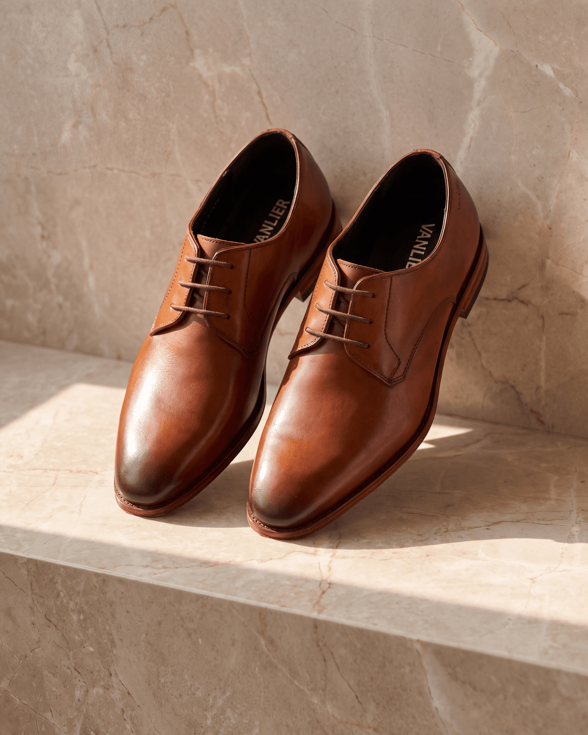 Cognac gladleren Madison veterschoen – het paar op warm marmer