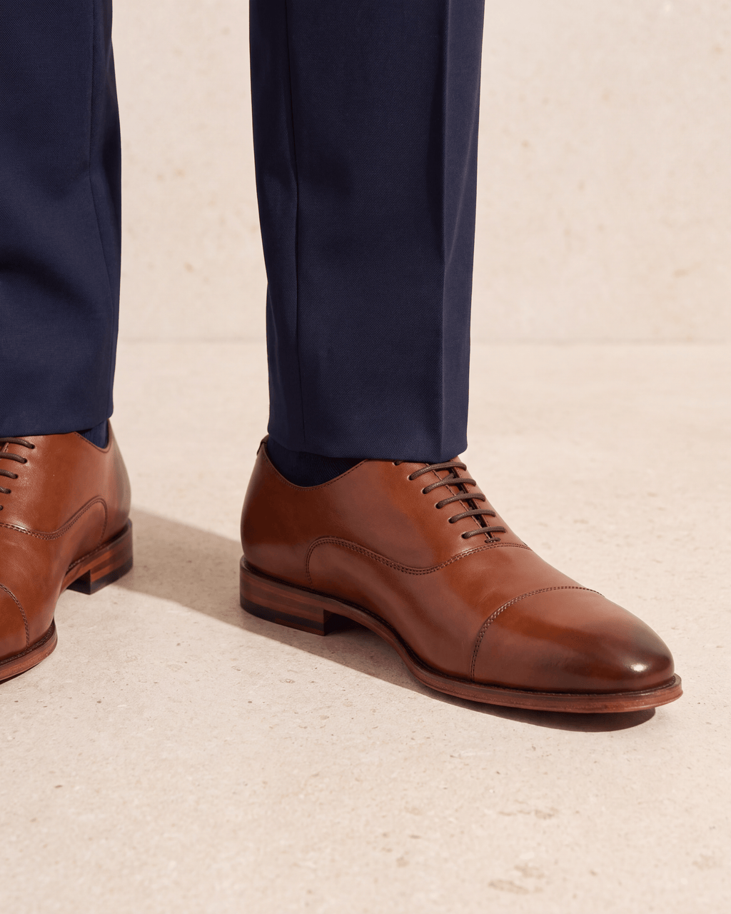 Cognac gladleren Madison veterschoen – het paar op een kalkstenen vloer