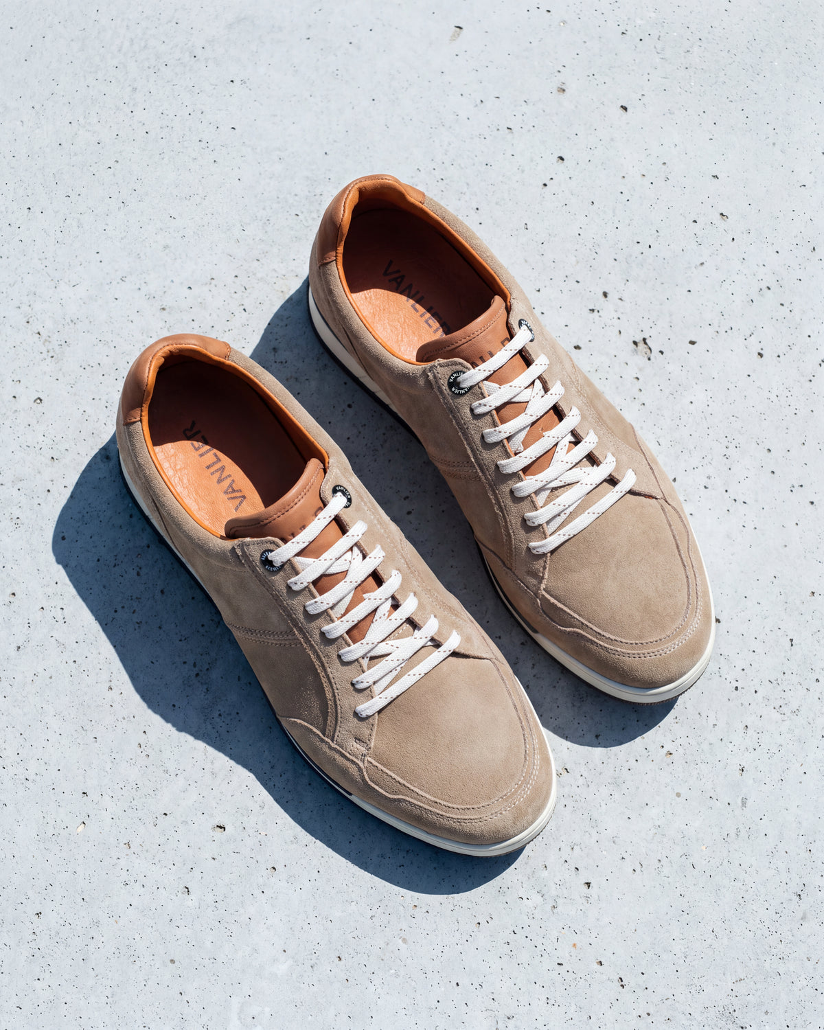 Zand beige suède Magnus sneaker – detail van het paar op ruw beton, andere hoek