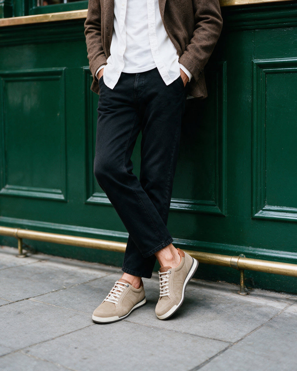 Zand beige suède Magnus sneaker – gedragen, leunend tegen de pui van een pub