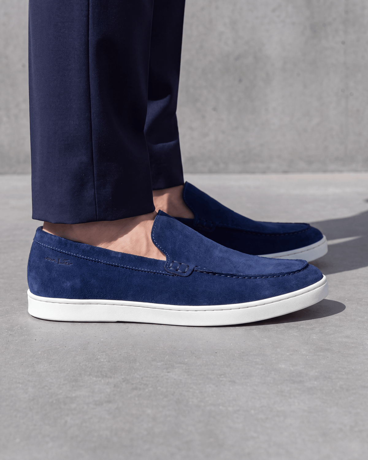 Blauw suède Lugano loafer – close-up van het paar op ruw beton