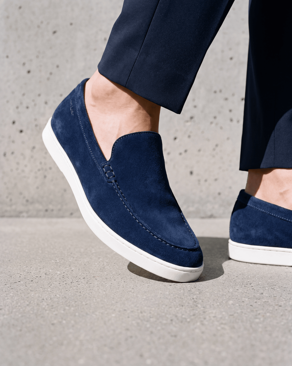 Blauw suède Lugano loafer – close-up van het paar op ruw beton