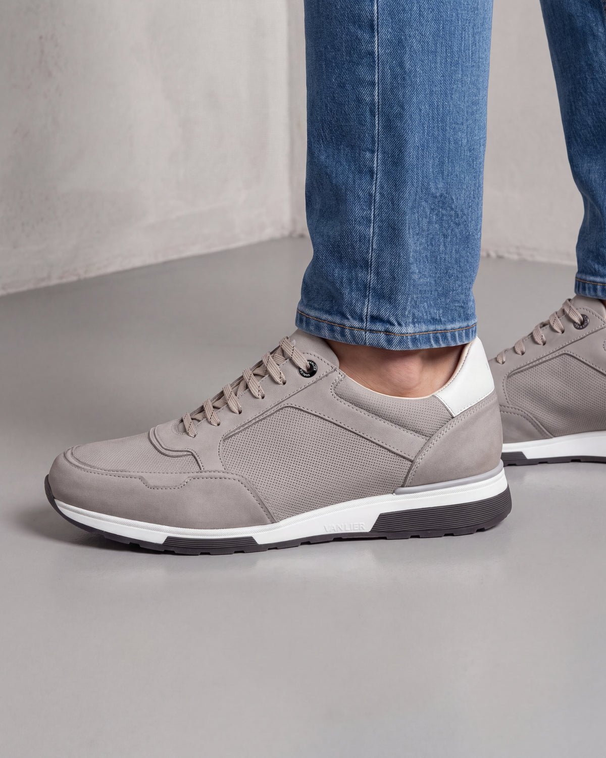 Lichtgrijs nubuck Positano sneaker – close-up van het paar op beton in een atelier