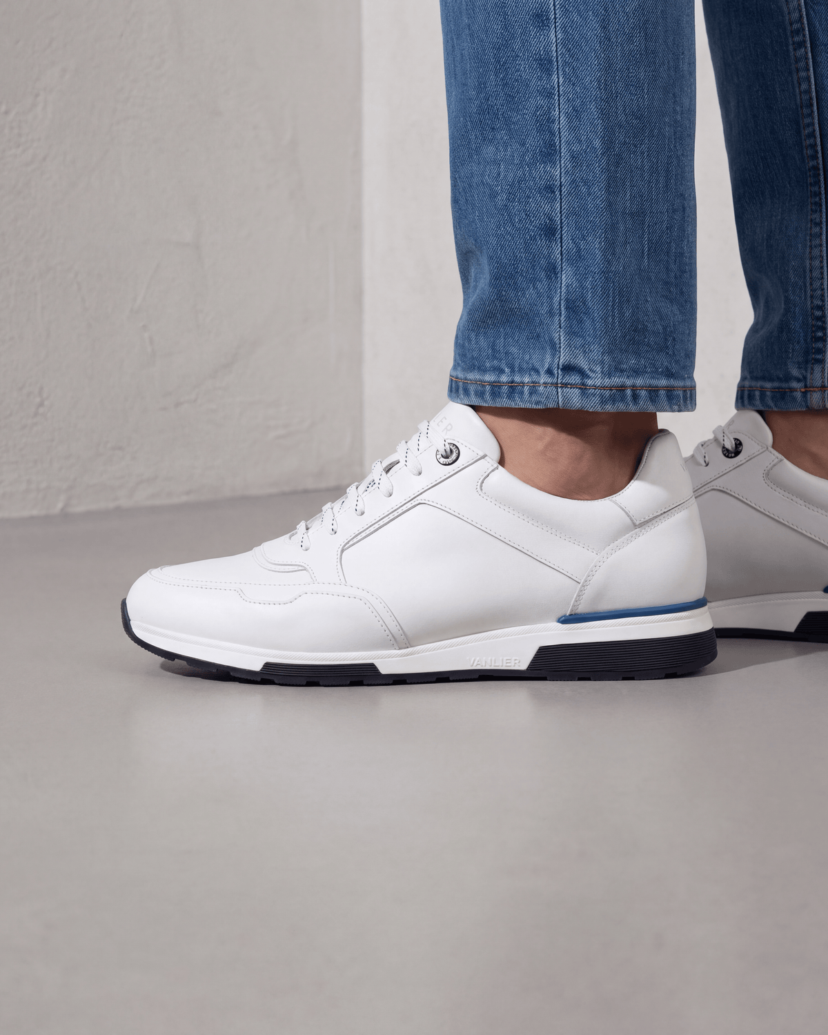 Wit gladleren Positano sneaker – close-up van het paar op beton in een atelier