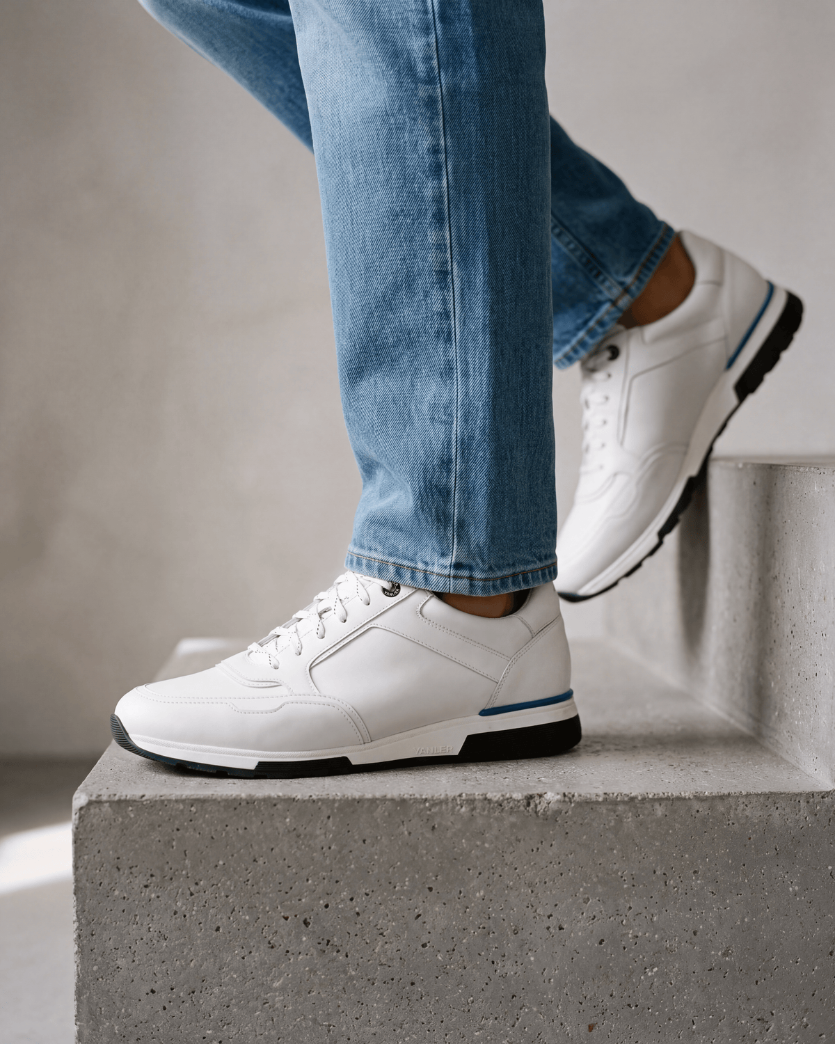 Wit gladleren Positano sneaker – close-up van het paar op beton in een atelier