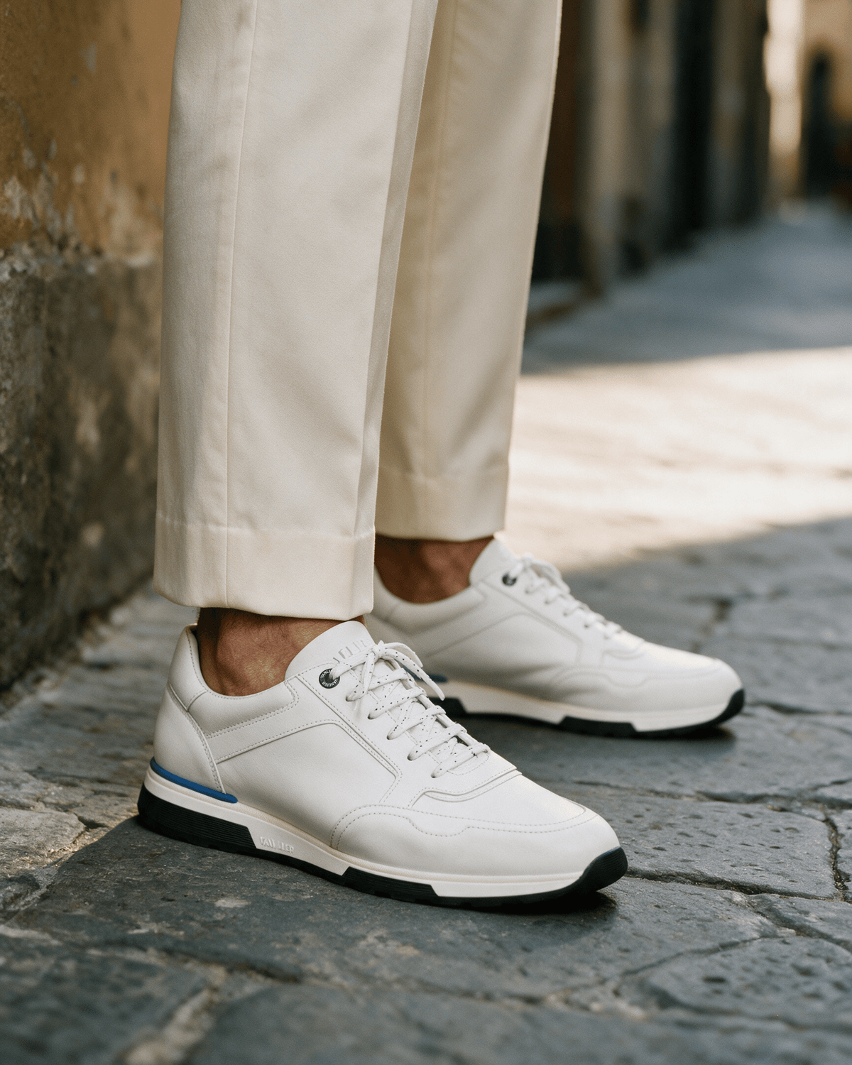 Wit gladleren Positano sneaker – gedragen, close-up op steen